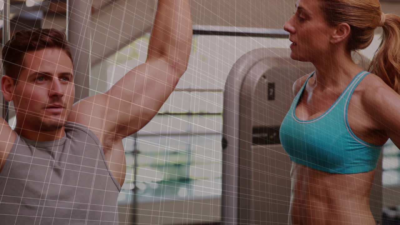 Male trainee gripping bar and performing pulldowns in gym, trainer guiding, red graph tracking form