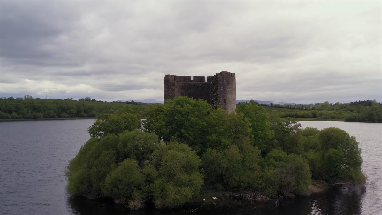 Dolly udara halus lambat dari pengambilan gambar pembuka Kastil Cloughoughter yang tenang dengan dua angsa di dasar kastil, Lough Oughter County Cavan Irlandia