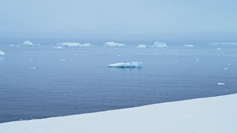 paisaje de invierno nevado con icebergs en la antártida, paisaje de nieve y iceberg en la península antártica mirando hacia el océano agua de mar desde el continente antártica tierra