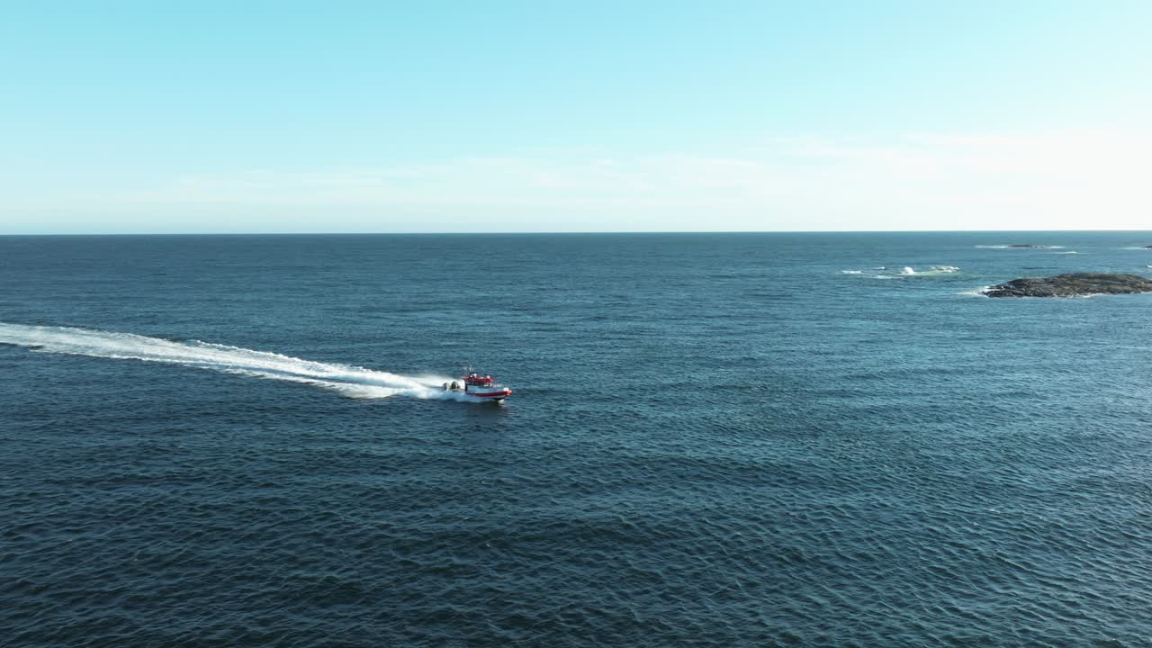 A small boat travels swiftly across the calm blue ocean, leaving a wake behind. The scene captures the vast sea under a bright sky, showcasing nature's beauty