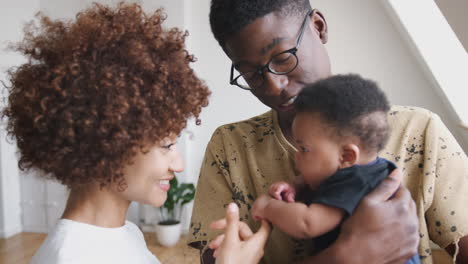 close up of loving parents holding newborn baby son at home in loft apartment