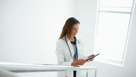 Female-Doctor-With-Digital-Tablet-Checking-Patient-Notes-On-Stairs-In-Hospital