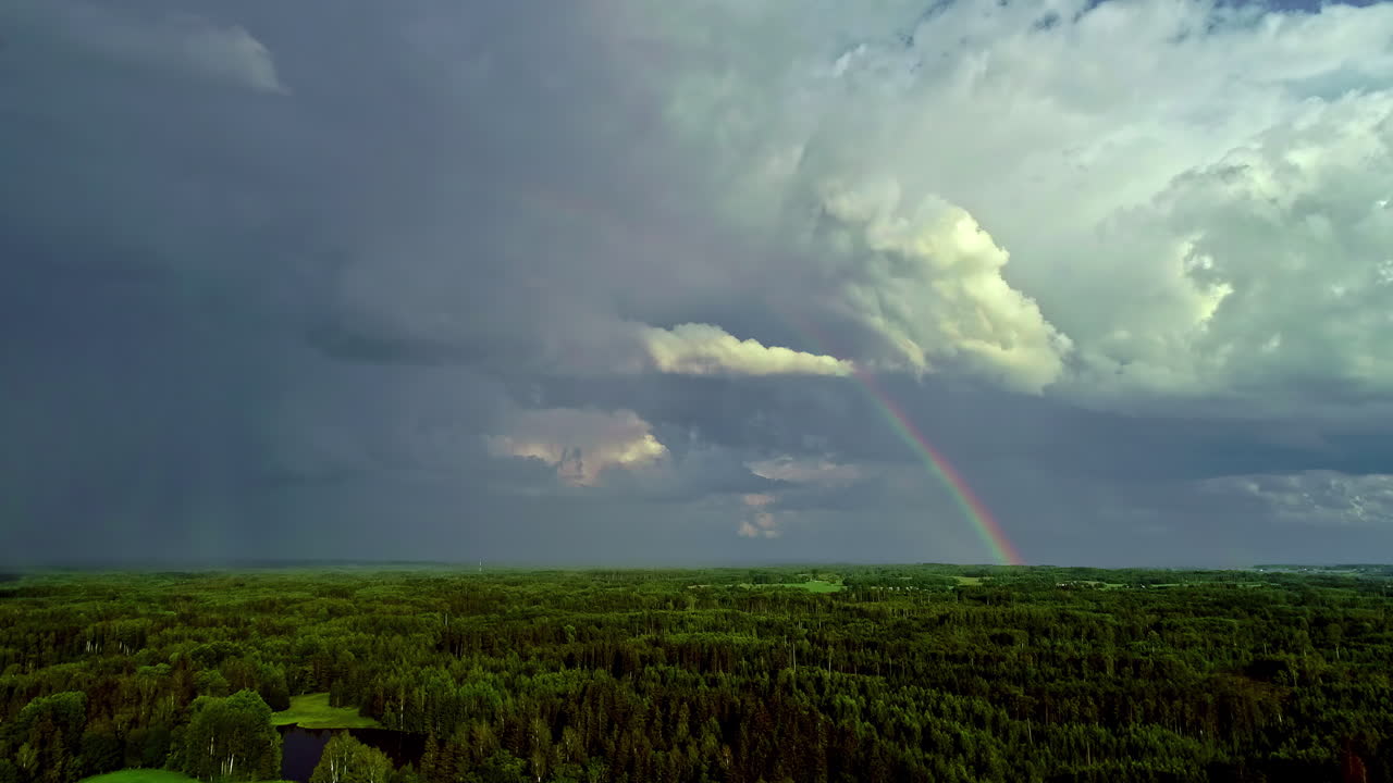 vista aérea sobre el paisaje forestal durante el día nublado con arco iris en el cielo