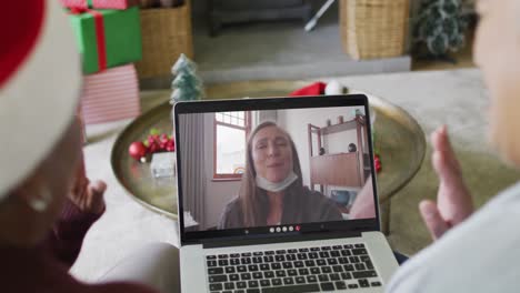 Diverse-senior-female-friends-using-laptop-for-christmas-video-call-with-happy-woman-on-screen