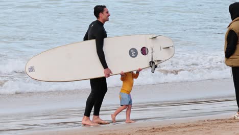 family walking with surfboard on the beach