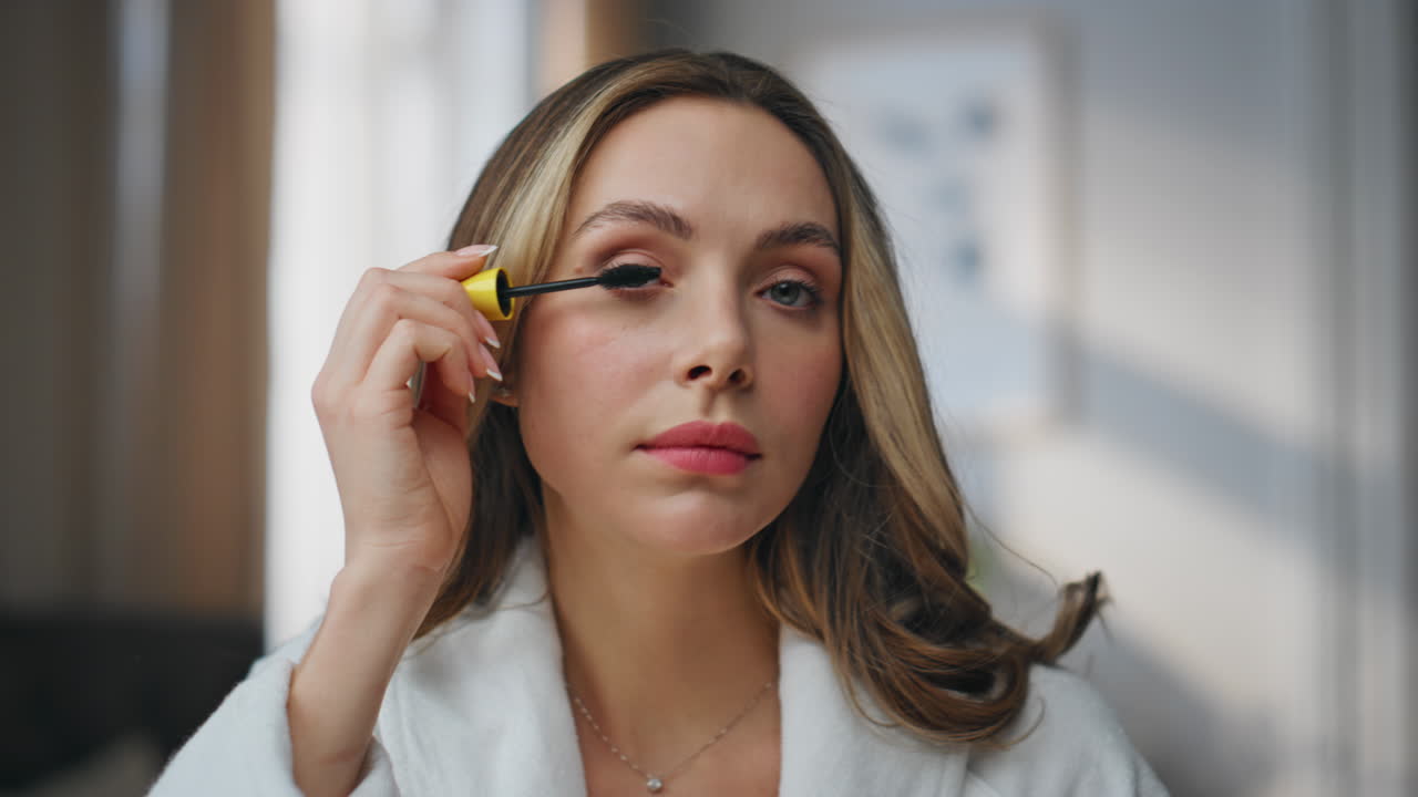 A woman applying makeup to her eyelashes