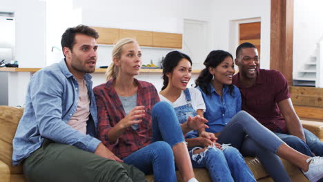 group of young friends watching sports on television and cheering