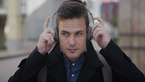 portrait attractive young businessman puts on headphones listening to music waiting on street enjoying relaxed urban lifestyle slow motion