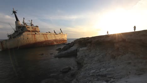 sunset over shipwreck on rocky coast