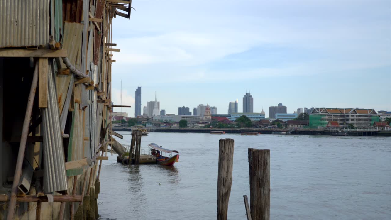Shot of the corner of a stilt house on the Chao Phraya river with the new metropolis buildings visible as a contrast in the background.