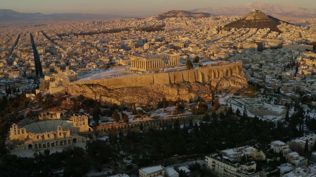 vista aérea alrededor de la colina de la acrópolis en atenas, durante una rara puesta de sol nevada - amplia, panorámica, órbita, disparo de drones