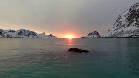 Aerial-drone-view-of-horizon-sunset-over-Haukland-fjord-water-surface-of-Lofoten-Islands-in-winter-season,-Norway