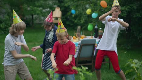 cheerful carefree children and teenagers dancing in slow motion at birthday party outdoors. happy caucasian boys and girls having fun celebrating holiday in spring summer park. lifestyle and childhood.