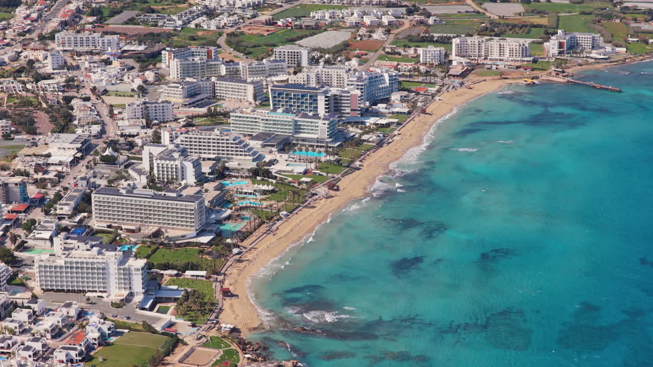 Vista aerea con drone di moderni hotel sul lungomare lungo la costa di Protaras, Cipro, con spiagge di sabbia dorata e acqua cristallina che attraggono turisti in questa destinazione mediterranea