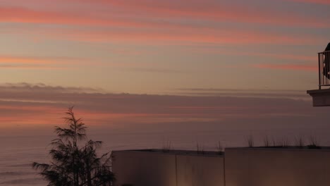 people standing on terras with fence enjoying the beautiful pink sky during sunset.