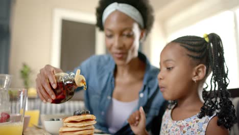 Happy-african-american-mother-and-daughter-having-breakfast,-in-slow-motion