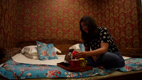 mujer revisa el contenido dentro de coloridas tazas de cerámica china mientras está sentada en una cama tradicional kang
