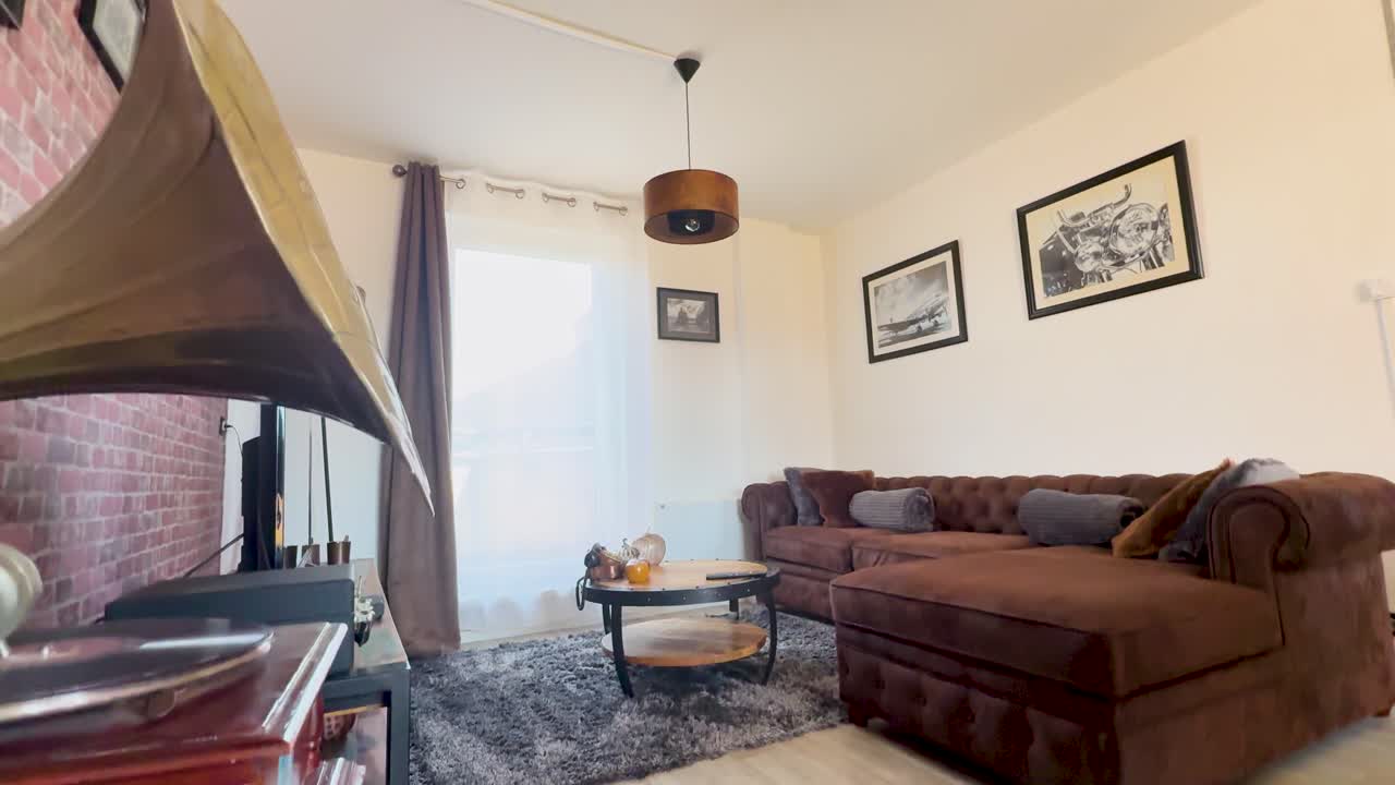A camera smoothly pans across a vintage-inspired apartment lounge, highlighting antique decor, a gramophone, brown sectional sofa, and soft natural lighting