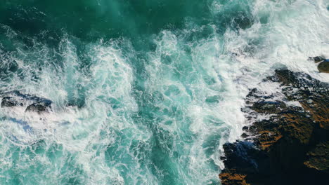 aerial view waves breaking at coastal rocks in slow motion. dramatic foamy sea