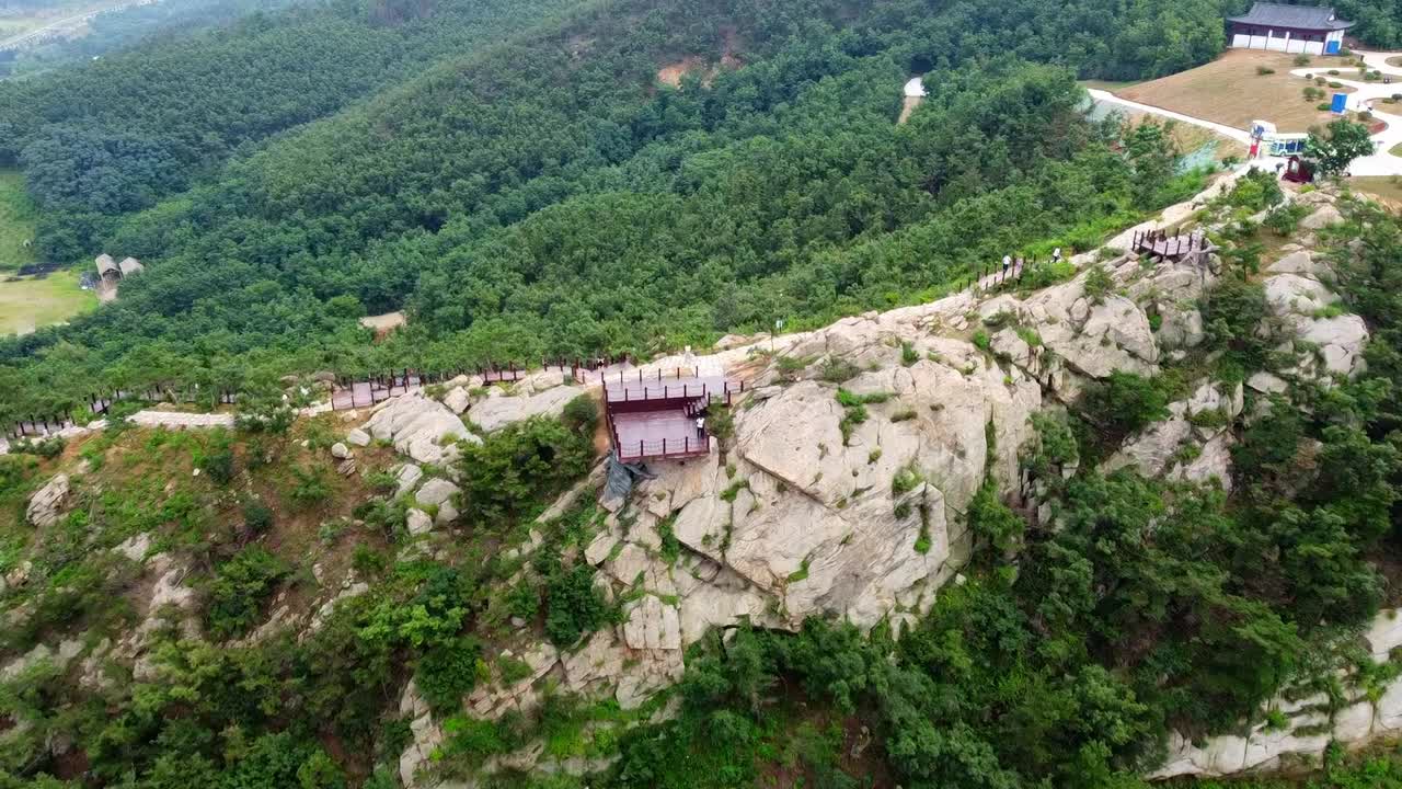 vista aérea dinámica de descenso del piloto de avión no tripulado africano negro con camisa blanca de pie en el observatorio del acantilado de huaxiacheng