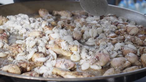 disparo en cámara lenta de un chef moviendo una sartén grande llena de peces y pollo