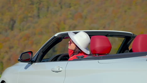 woman in convertible car enjoying scenic autumn drive