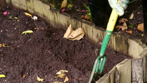 Person-mixing-soil-with-fork-in-garden