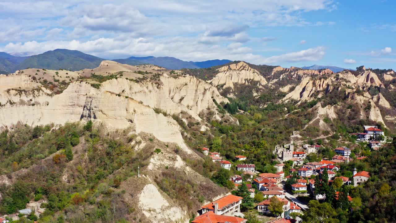 Aerial over small mountain town with pyramid rock formation landscape