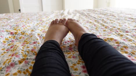 closeup of feet resting on a floral bedspread