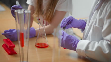 primer plano de un maestro y una colegiala haciendo un experimento científico en el aula.