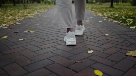 Man-feet-walking-along-autumn-park-in-daytime