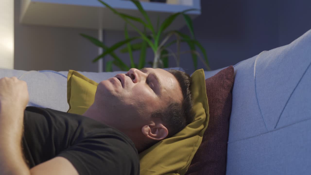 hombre sentado en el sofá en casa sufriendo de depresión.