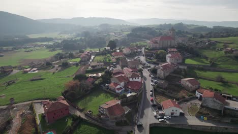 Beautiful-historic-Spanish-village-with-a-large-church-prominent-in-the-village-center-near-Valles-Pasiegos-with-the-silhouettes-of-the-vast-nature-in-the-background