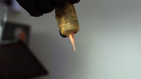 close up cámara lenta tomada de mano de la mano de un artista del tatuaje preparando su herramienta de pistola de aguja para una sesión de cliente envolviendo en cinta para crear un agarre de mano