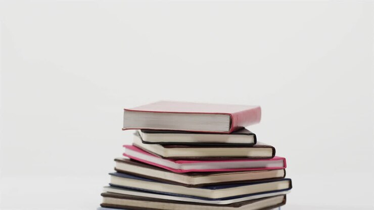 Primo piano di una pila di libri su sfondo bianco, al rallentatore.