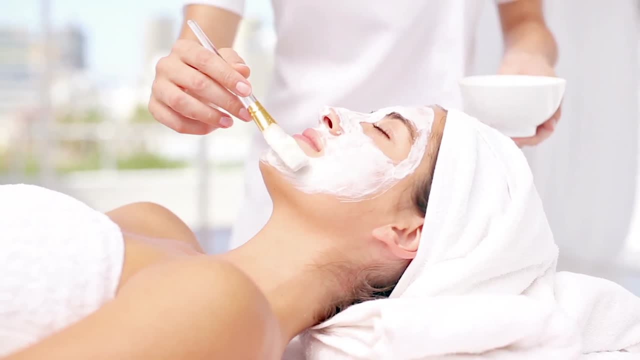 아름다운 갈색 여성이 얼굴 치료를 받고 있습니다.