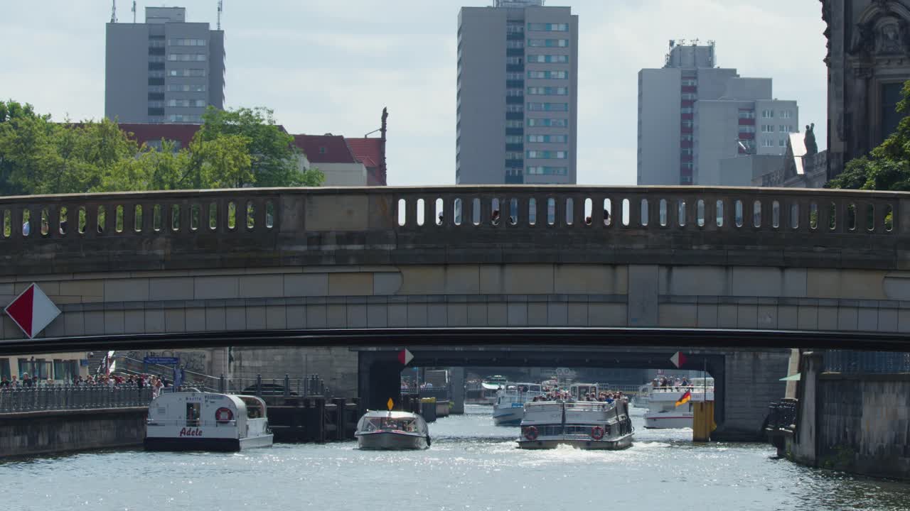 Daytime cityscape with boats moving beneath urban bridge, modern buildings, and soft natural lighting