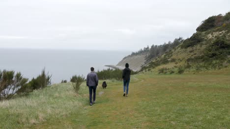 Couple-walking-towards-the-beach-with-their-dog