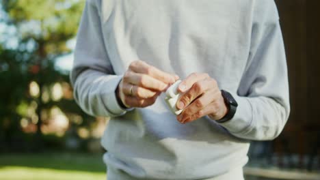 man putting earbuds in case in a garden