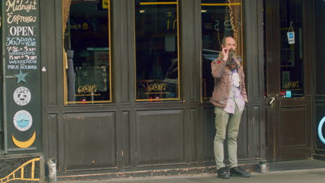 An excentric looking man smoking a cigarette outside Midnight Espresso cafe, Cuba St, Wellington, New Zealand.