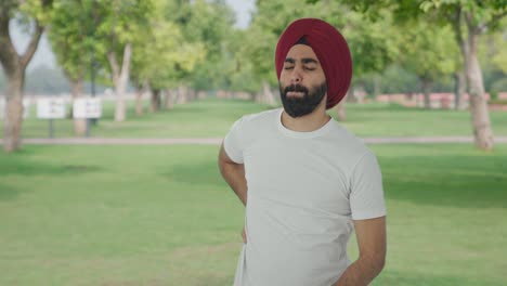sick sikh indian man suffering from back pain in park