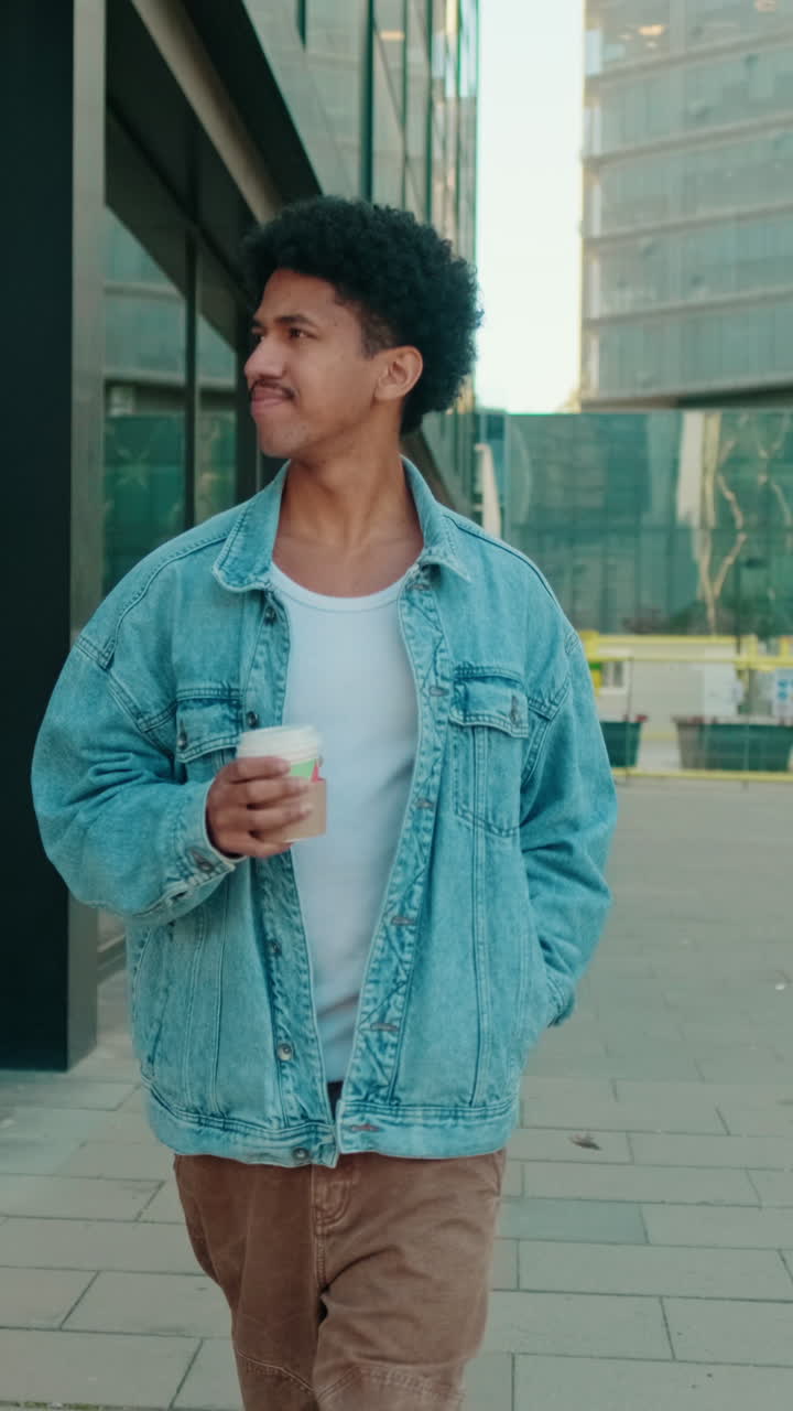 Ung mand går med kaffekop i bymiljø