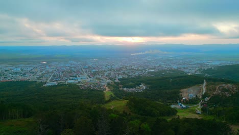 aerial view of a city at sunset with surrounding mountains and forest