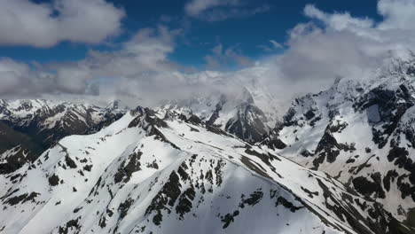 vuelo aéreo a través de nubes montañosas sobre hermosos picos nevados de montañas y glaciares.