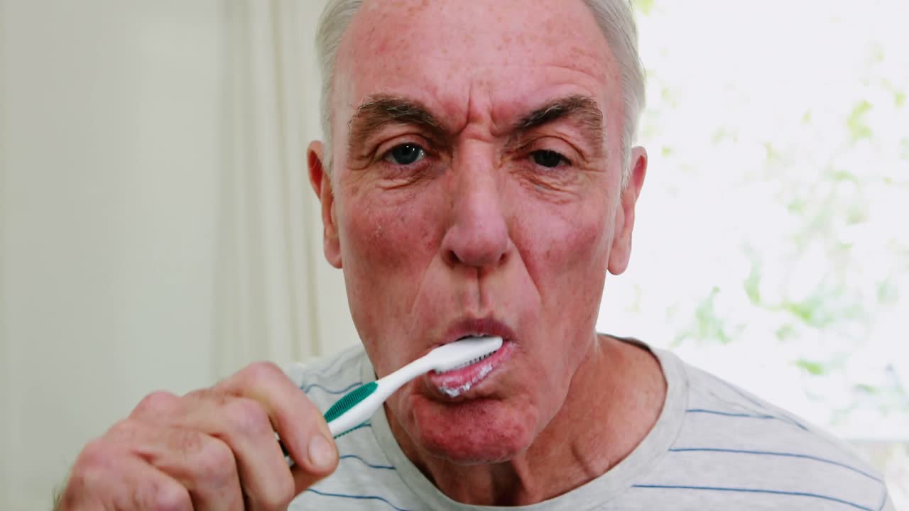 Senior man brushing his teeth in bathroom