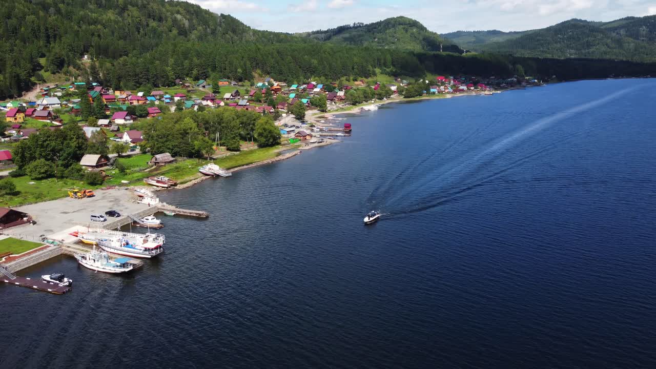 은 날 에 산악 한 호수 수면 을 따라 이동 하는 관광 보트 의 공중 사진