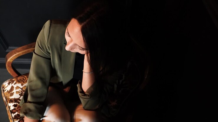 Triste donna bruna seduta su una poltrona che parla, con la testa china verso il pavimento