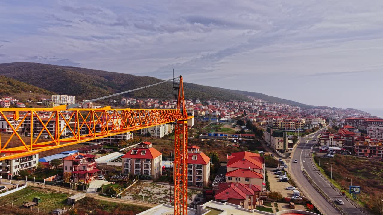 Gru da costruzione torreggia su una città costiera con viste panoramiche