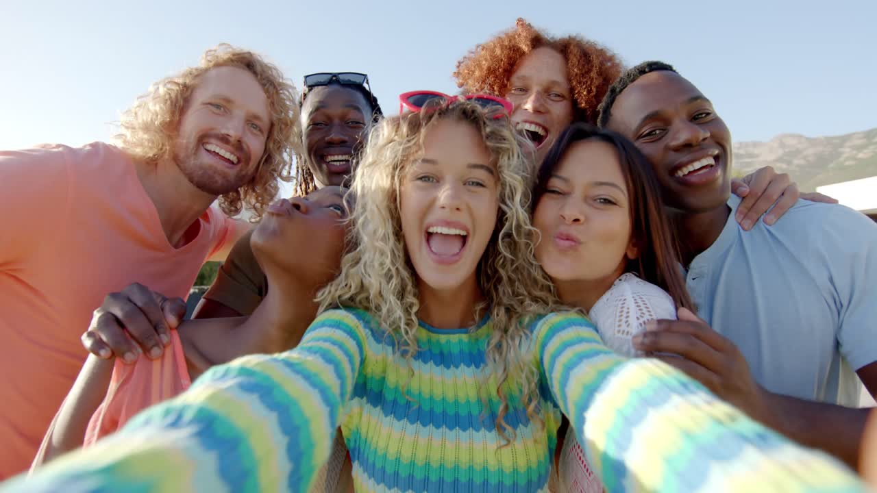 retrato de amigos felices y diversos abrazados tomando una selfie de grupo en una fiesta soleada en la piscina, cámara lenta