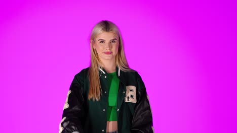 young blonde woman waving hand, greeting gesture against purple color background, studio shot